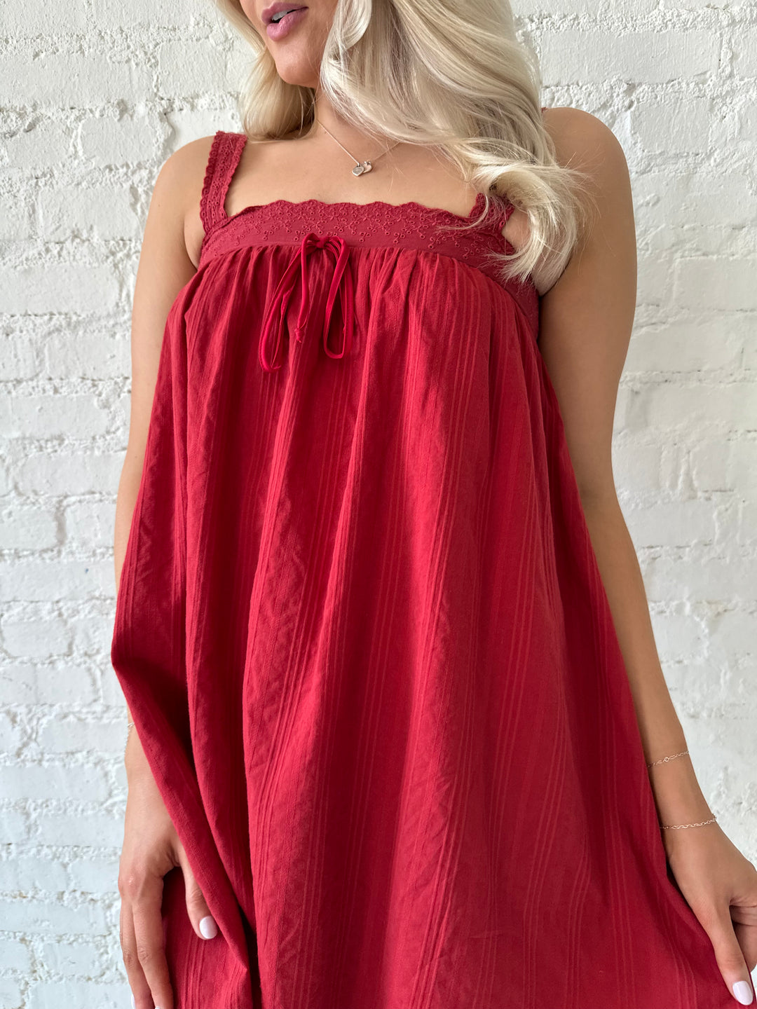 Woman wearing red shift mini dress with textured trim detail.