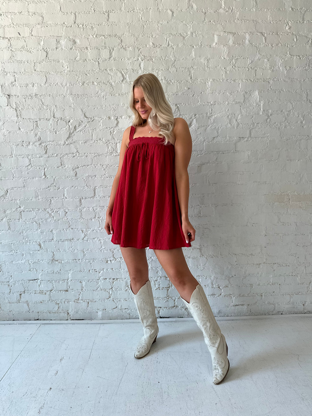 Woman wearing red shift mini dress with textured trim detail.