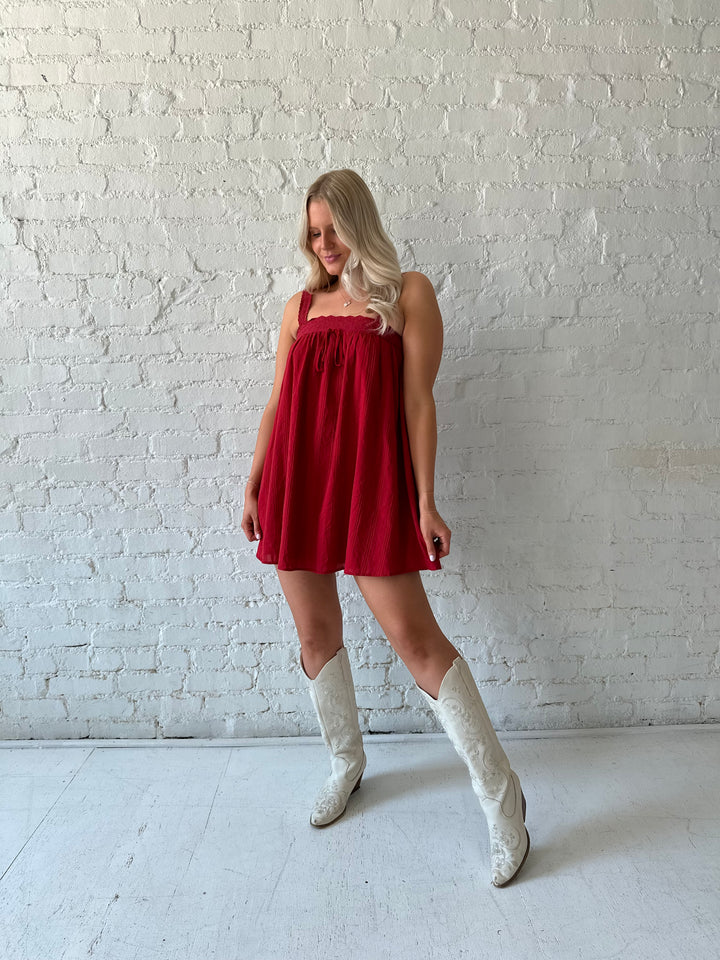 Woman wearing red shift mini dress with textured trim detail.
