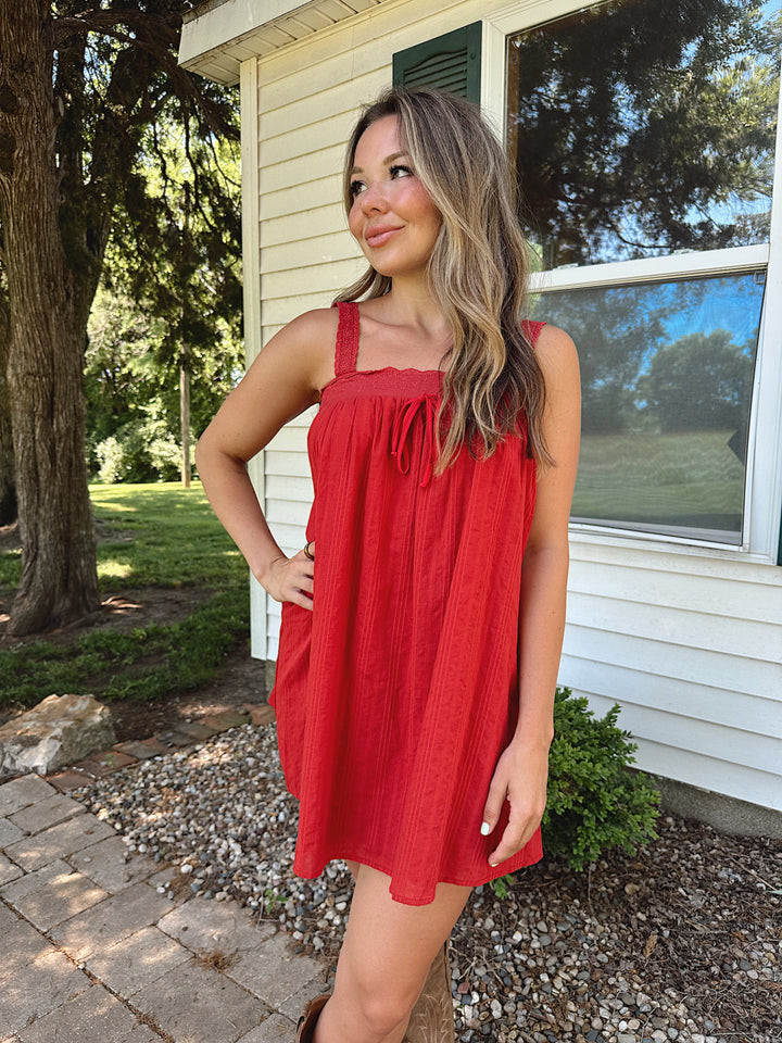 Woman wearing red shift mini dress with textured trim detail.
