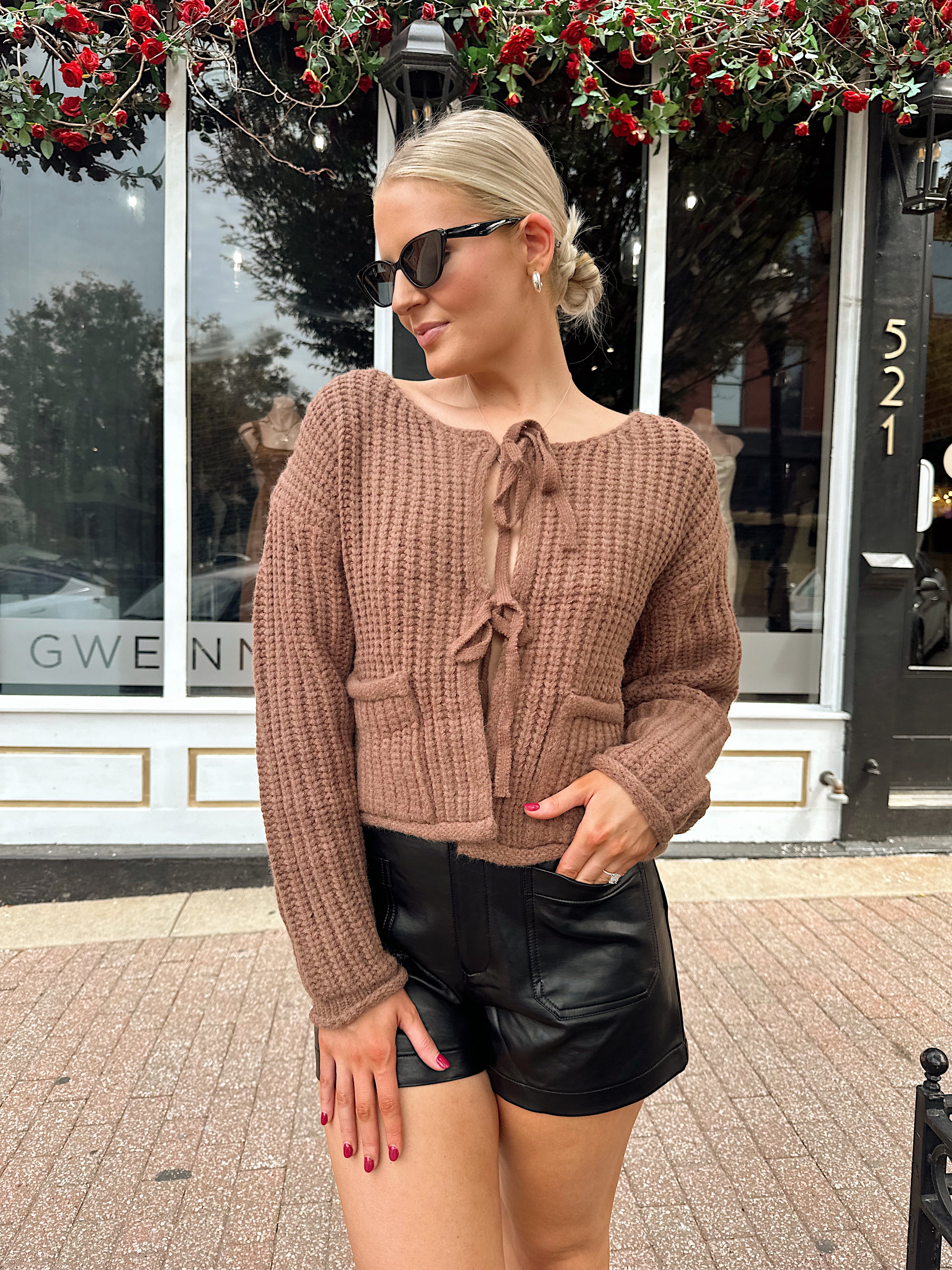 Woman wearing mocha brown knit front tie cardigan with functional front pockets.