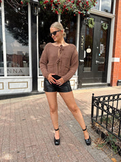 Woman wearing mocha brown knit front tie cardigan with functional front pockets.