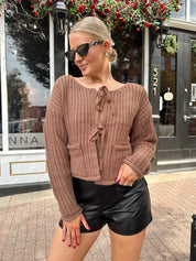 Woman wearing mocha brown knit front tie cardigan with functional front pockets.