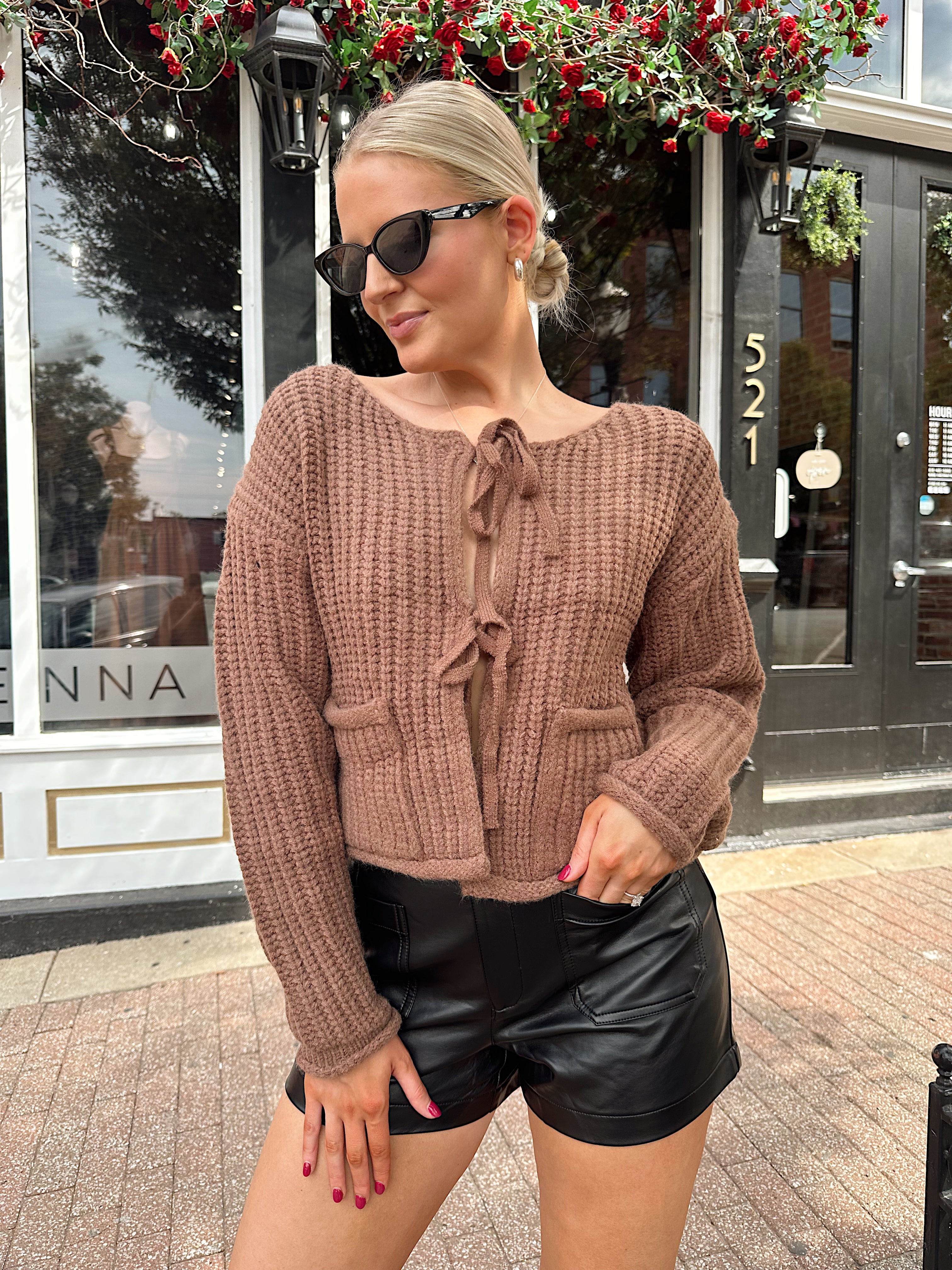 Woman wearing mocha brown knit front tie cardigan with functional front pockets.