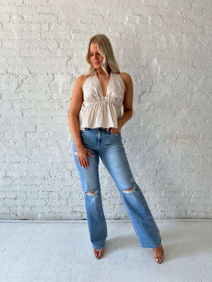 Woman wearing brown striped halter top with low back, and gathering detail.