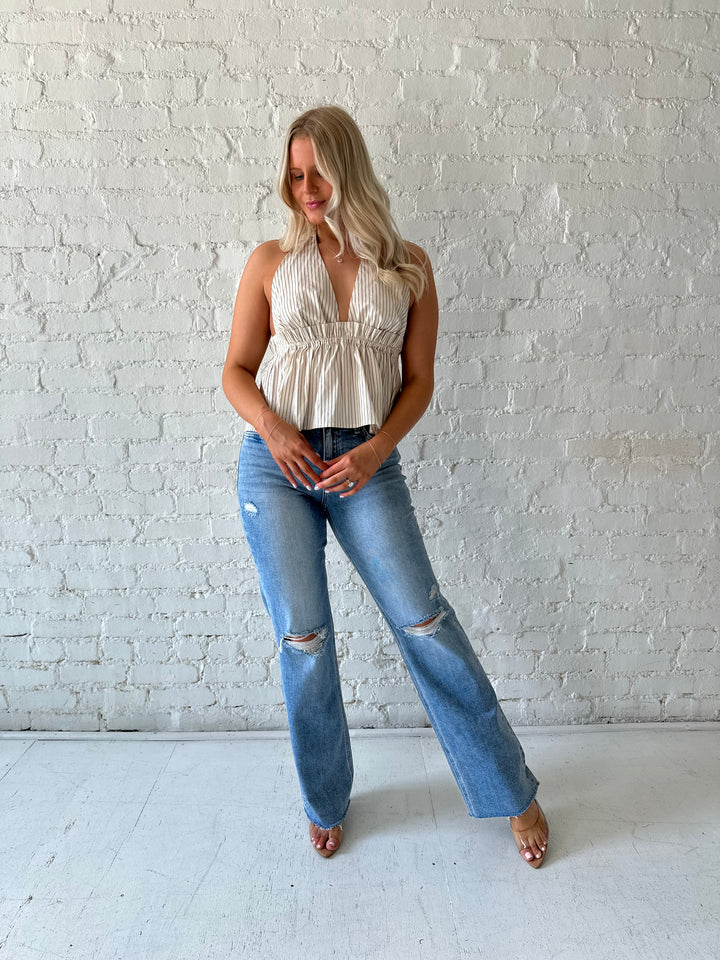 Woman wearing brown striped halter top with low back, and gathering detail.