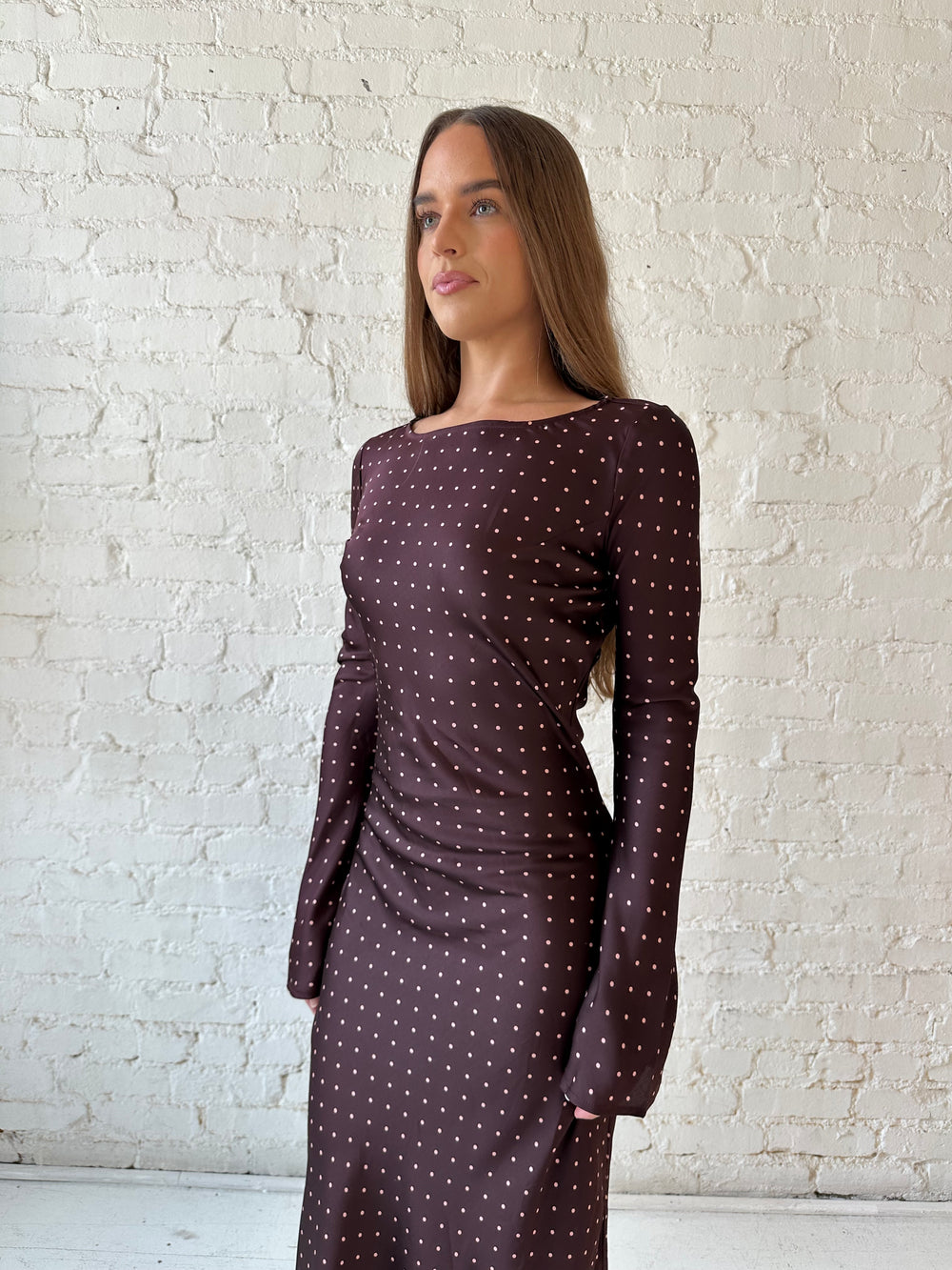 Woman wearing a burgundy polka dot  long sleeve satin maxi dress with heels.