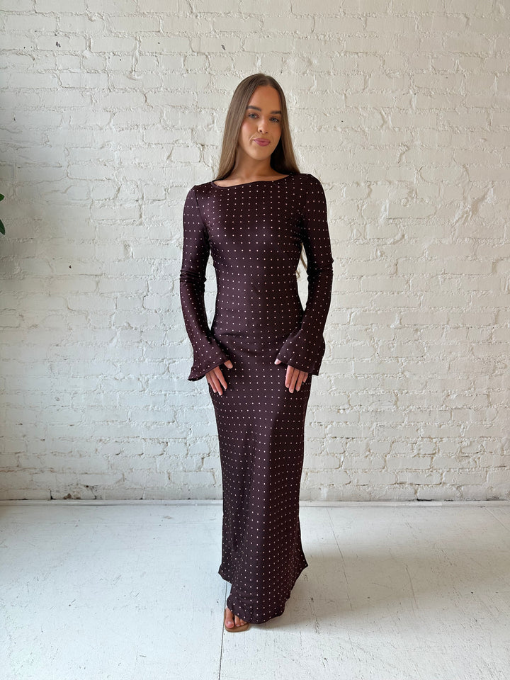 Woman wearing a burgundy polka dot  long sleeve satin maxi dress with heels.