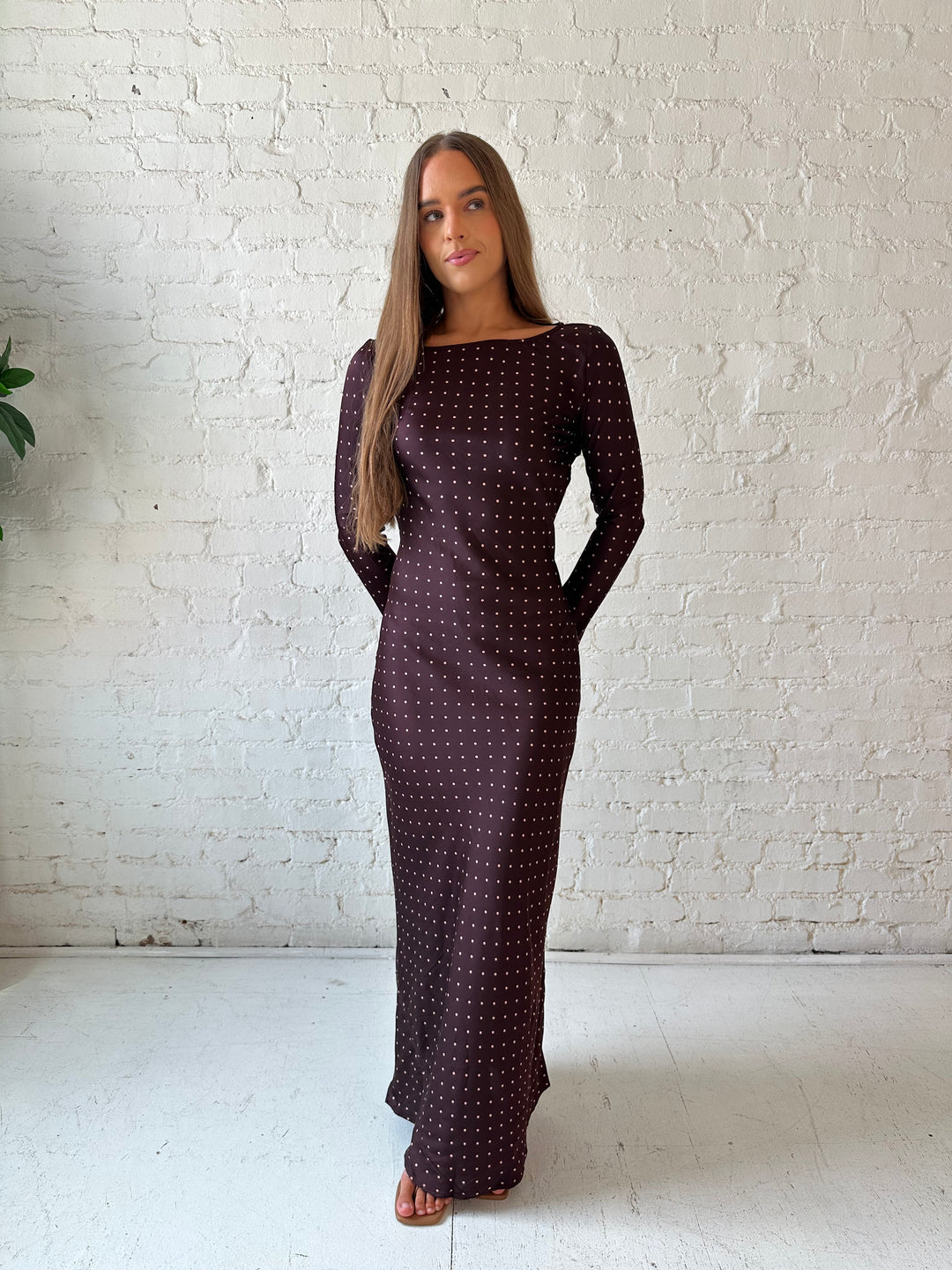 Woman wearing a burgundy polka dot  long sleeve satin maxi dress with heels.