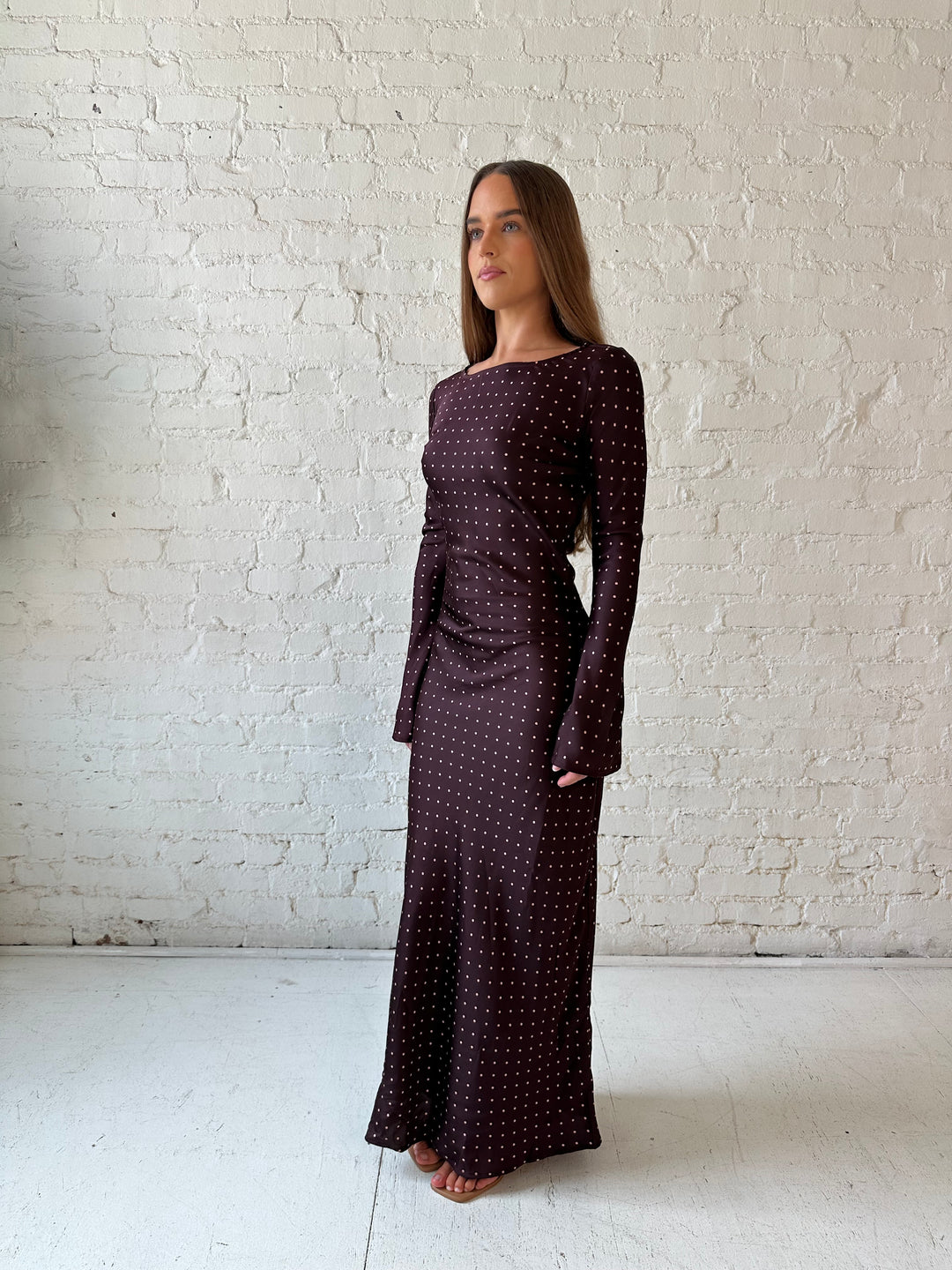 Woman wearing a burgundy polka dot  long sleeve satin maxi dress with heels.