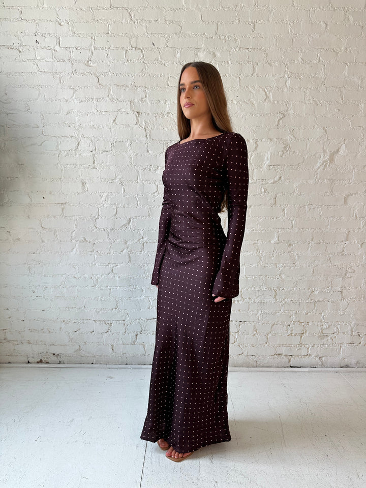 Woman wearing a burgundy polka dot  long sleeve satin maxi dress with heels.