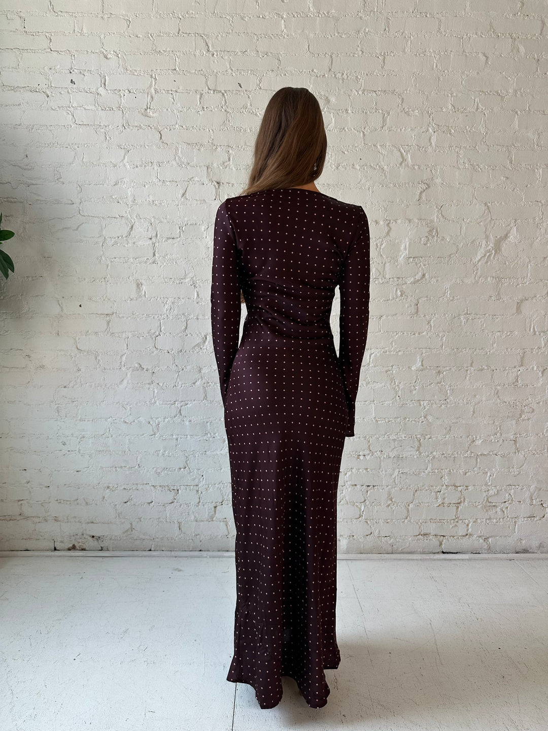 Woman wearing a burgundy polka dot  long sleeve satin maxi dress with heels.
