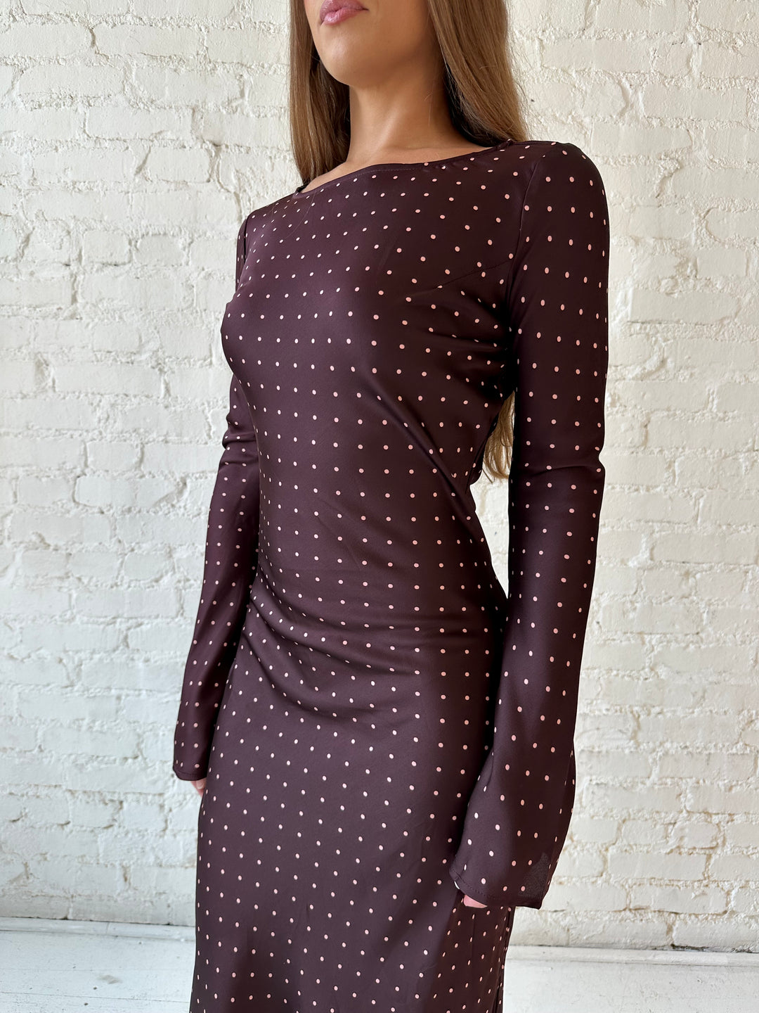Woman wearing a burgundy polka dot  long sleeve satin maxi dress with heels.
