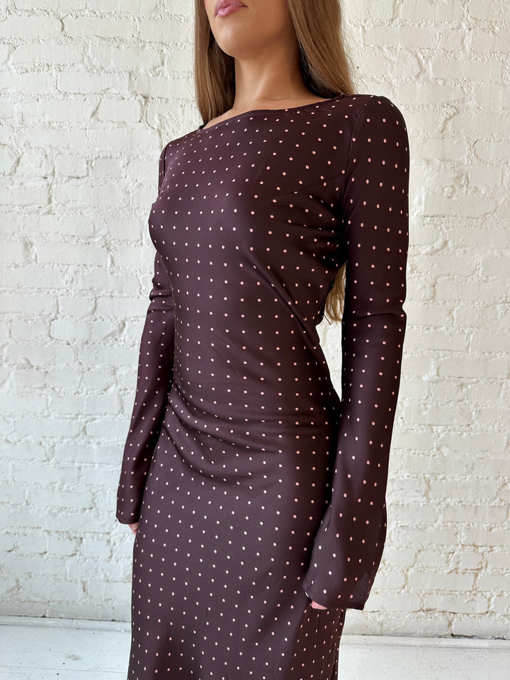 Woman wearing a burgundy polka dot  long sleeve satin maxi dress with heels.
