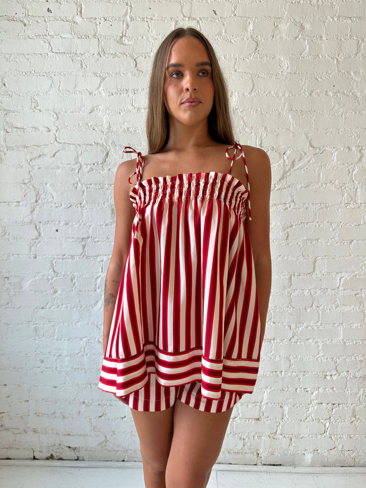 Woman wearing red striped two piece short set with smocked neckline detailing. 