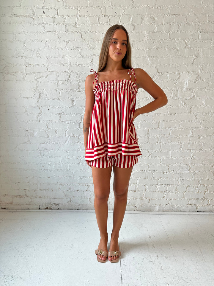 Woman wearing red striped two piece short set with smocked neckline detailing. 