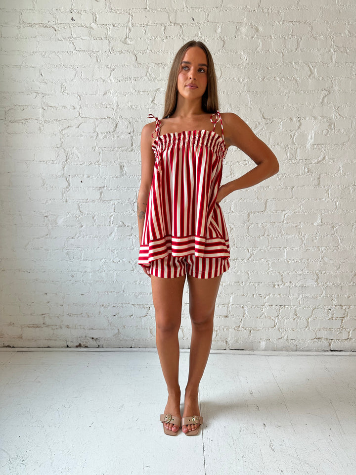 Woman wearing red striped two piece short set with smocked neckline detailing. 