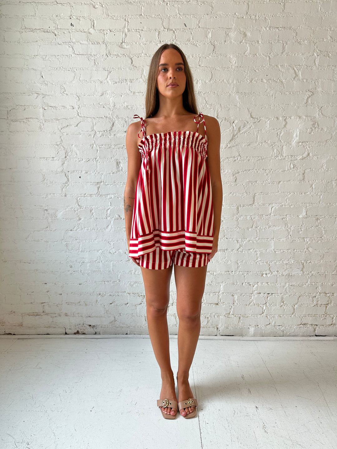 Woman wearing red striped two piece short set with smocked neckline detailing. 