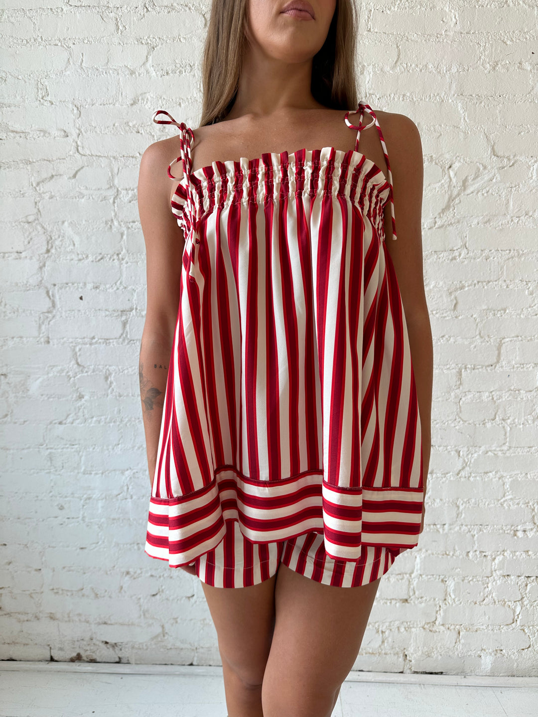Woman wearing red striped two piece short set with smocked neckline detailing. 