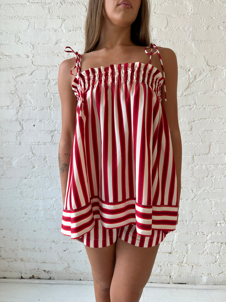 Woman wearing red striped two piece short set with smocked neckline detailing. 