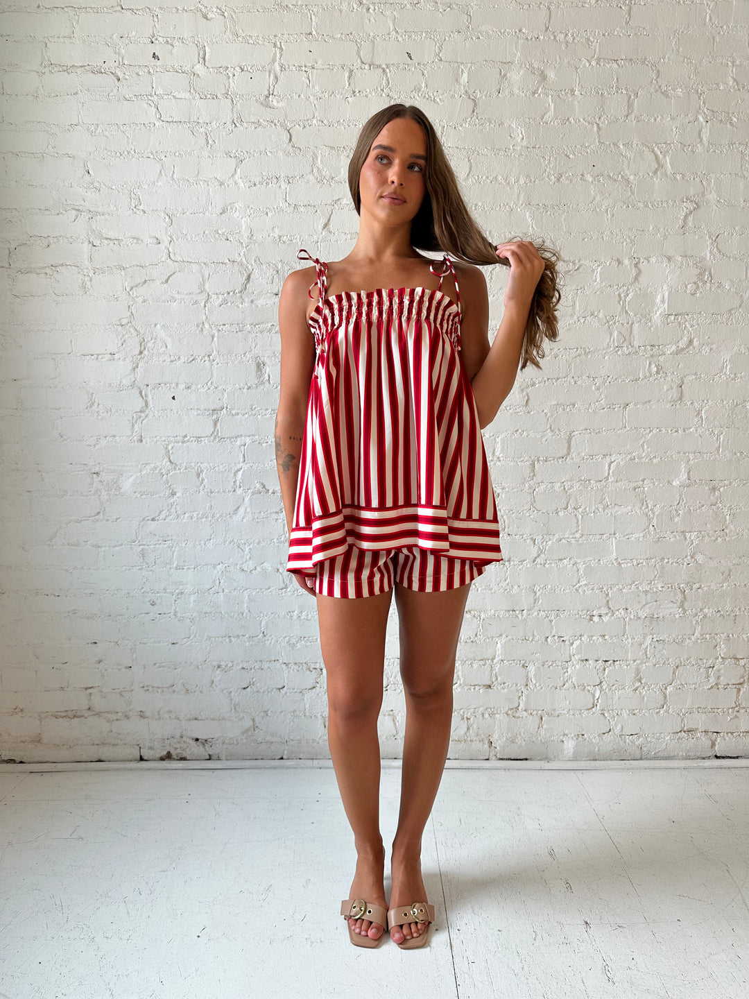 Woman wearing red striped two piece short set with smocked neckline detailing. 