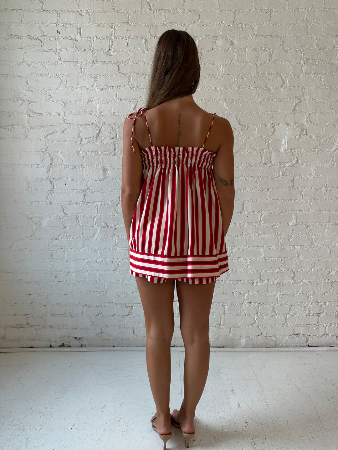 Woman wearing red striped two piece short set with smocked neckline detailing. 