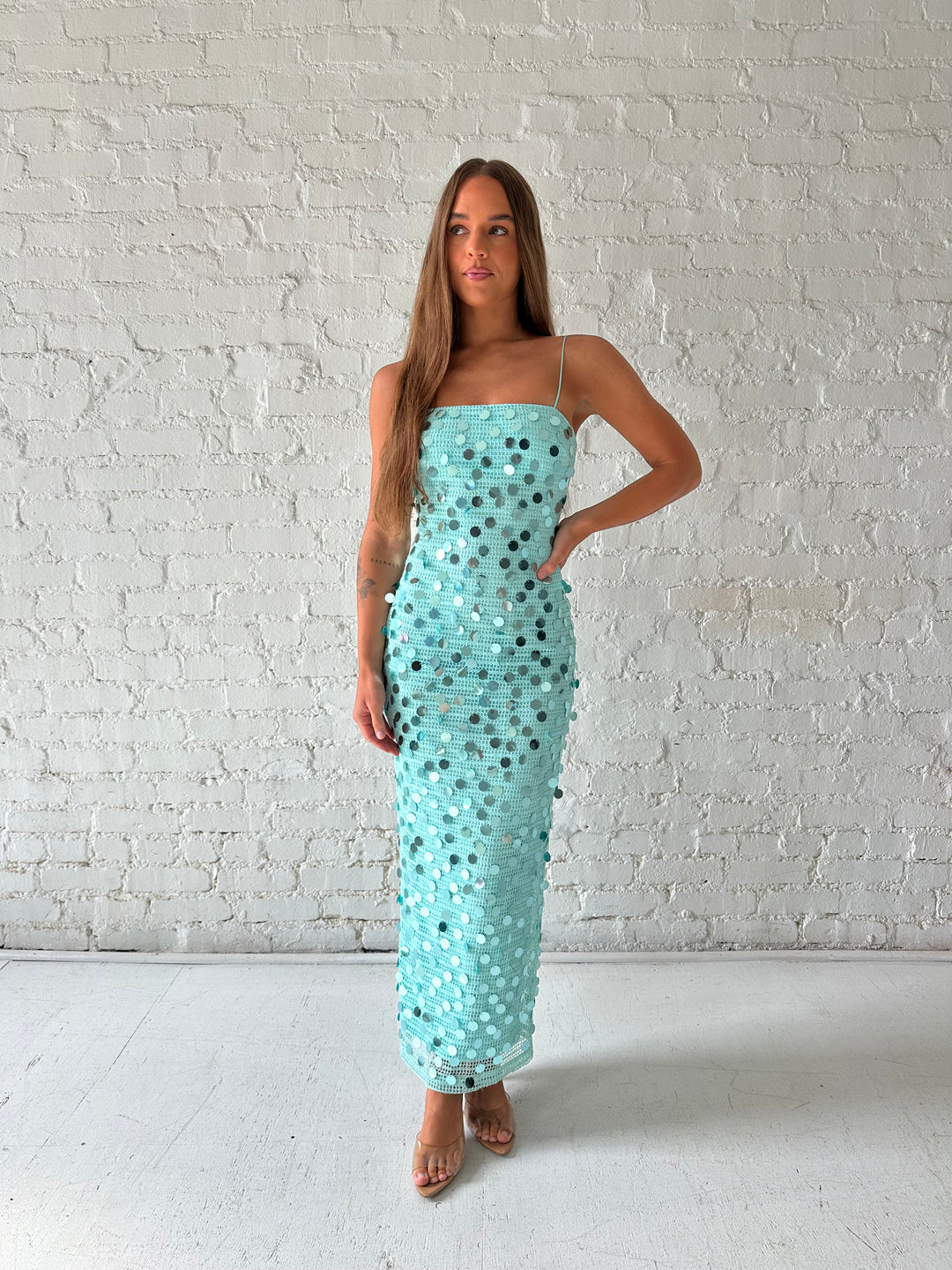 Woman wearing teal knit midi dress with sequin overlay. 