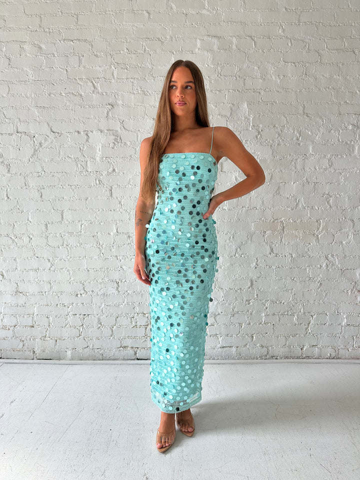 Woman wearing teal knit midi dress with sequin overlay. 