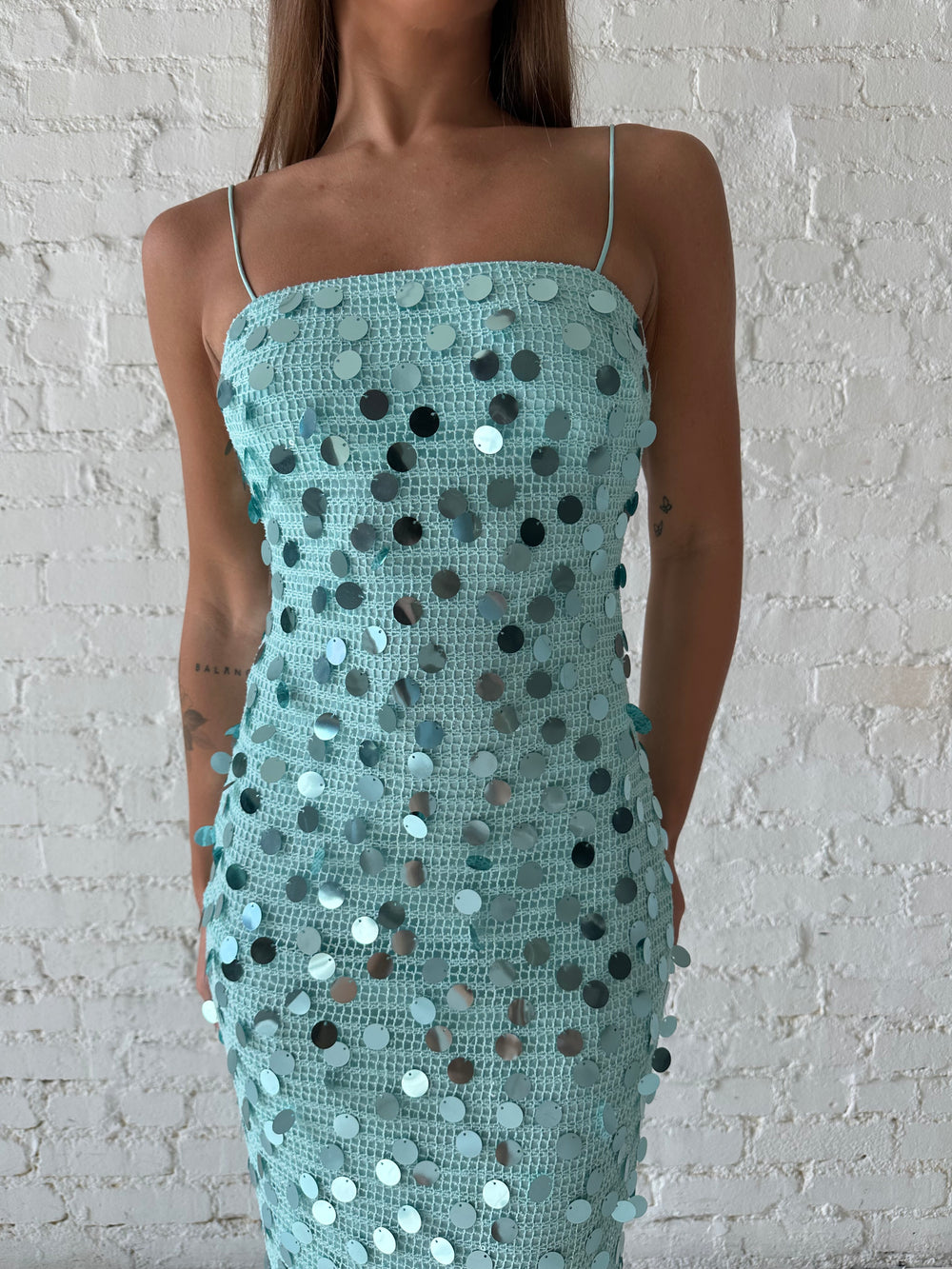 Woman wearing teal knit midi dress with sequin overlay. 