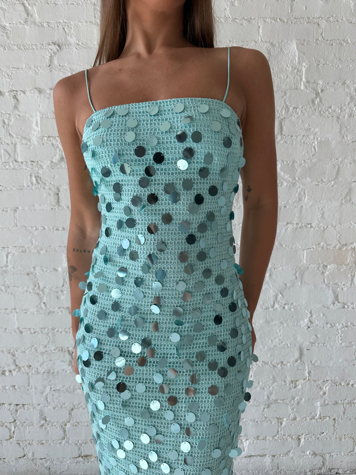 Woman wearing teal knit midi dress with sequin overlay. 