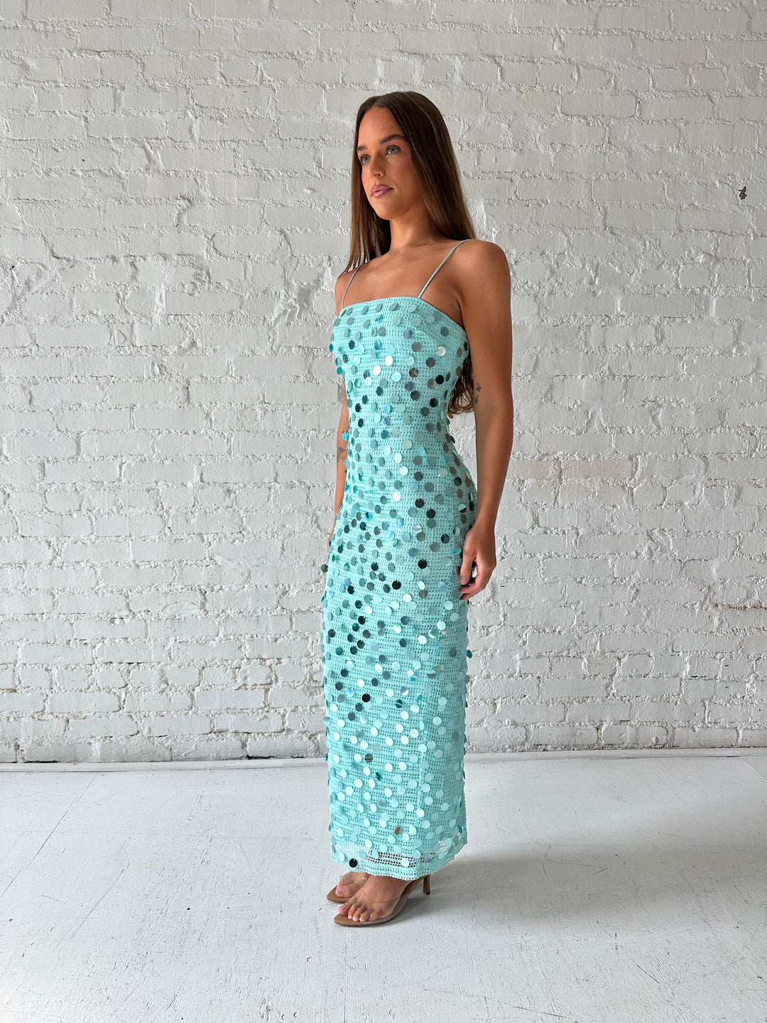 Woman wearing teal knit midi dress with sequin overlay. 