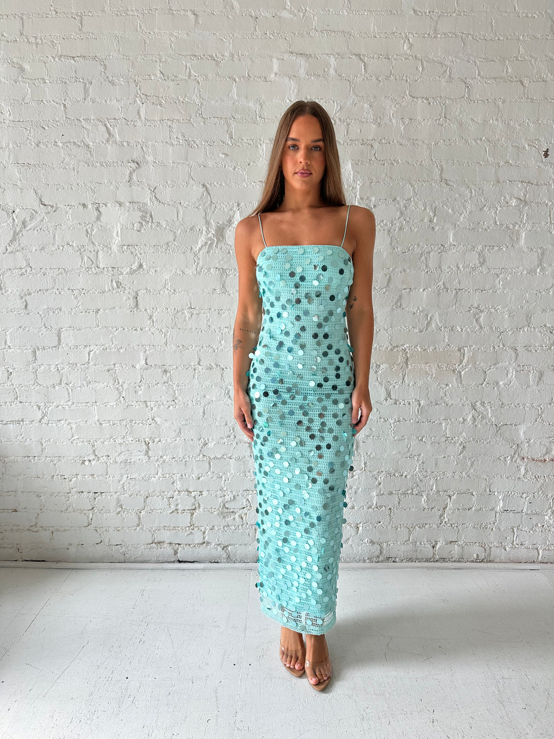 Woman wearing teal knit midi dress with sequin overlay. 