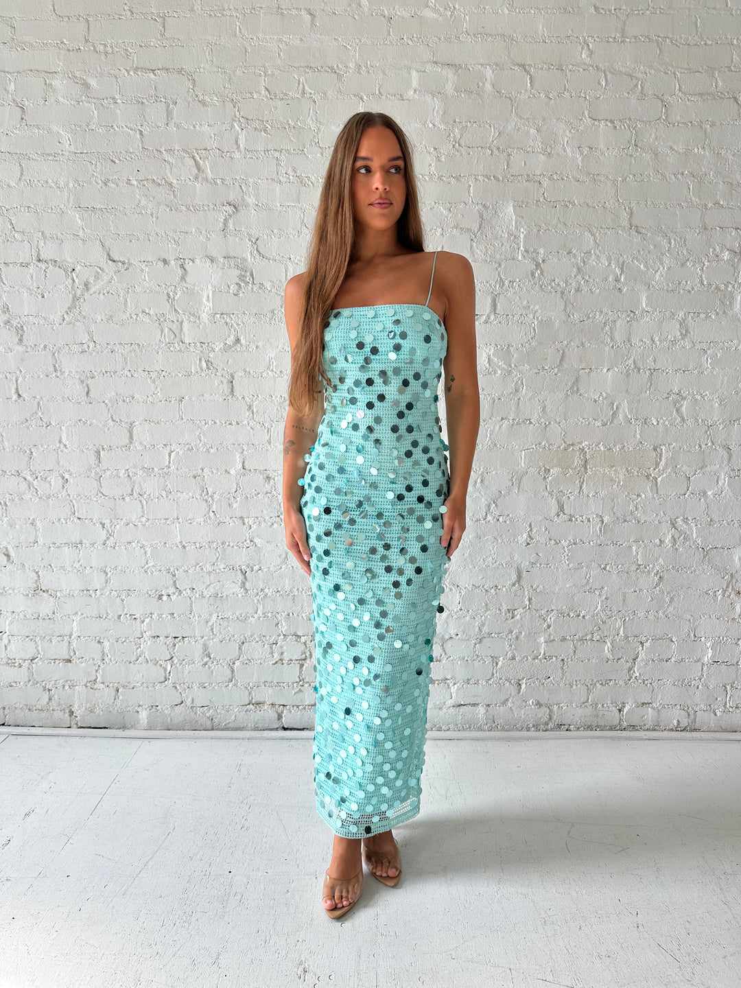 Woman wearing teal knit midi dress with sequin overlay. 