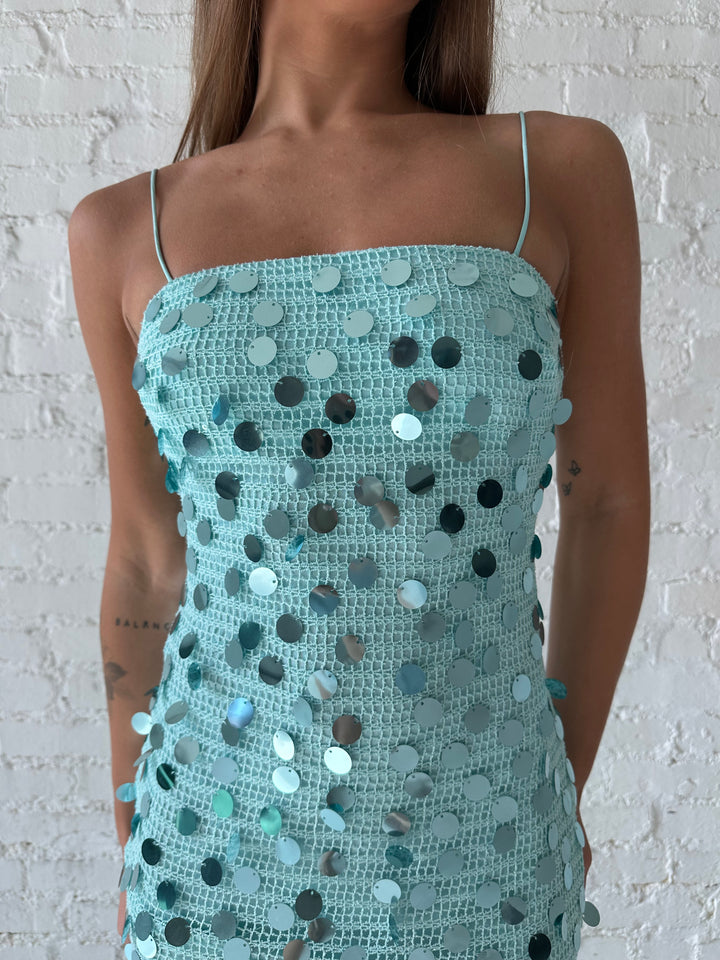 Woman wearing teal knit midi dress with sequin overlay. 