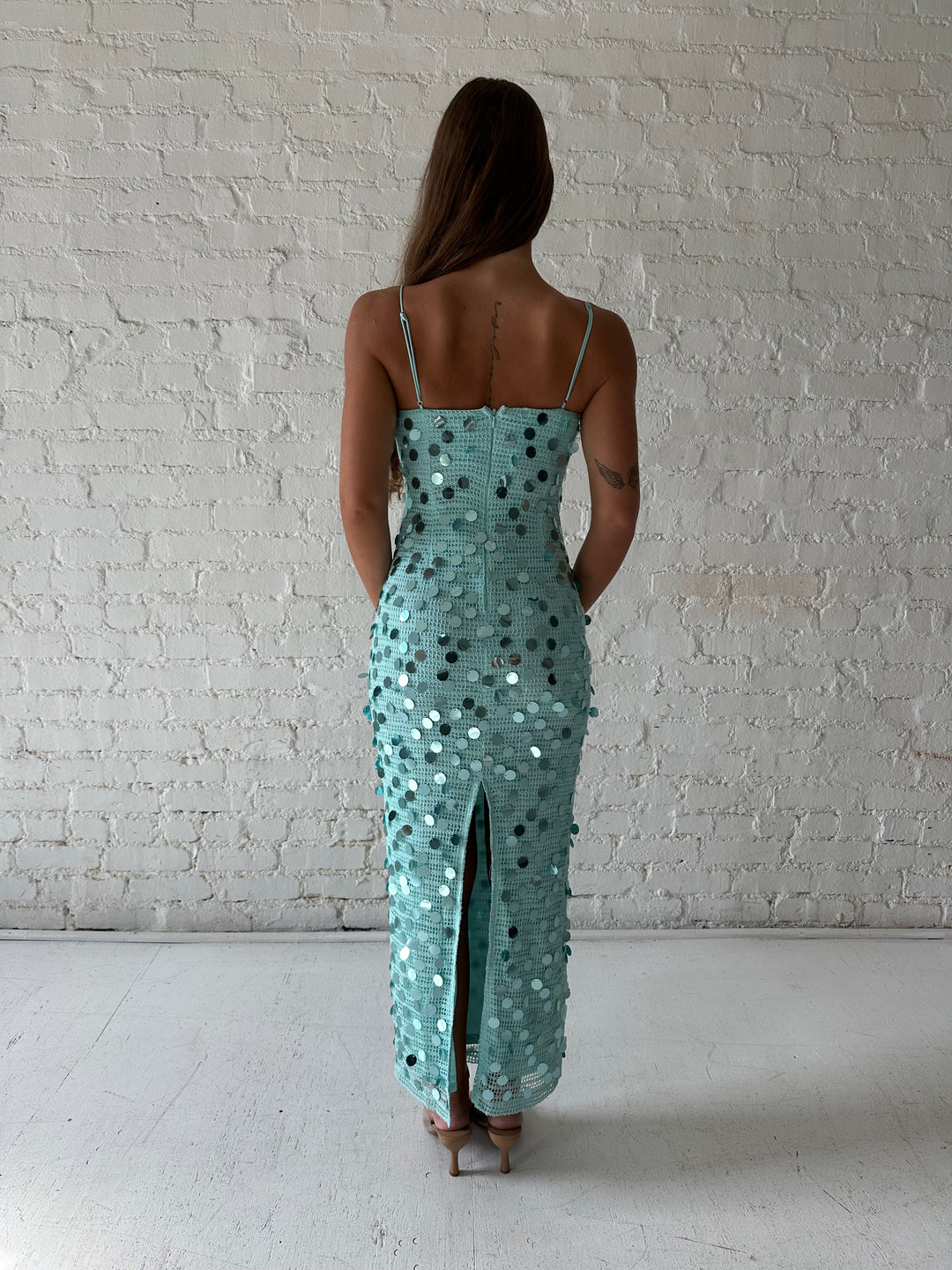 Woman wearing teal knit midi dress with sequin overlay. 