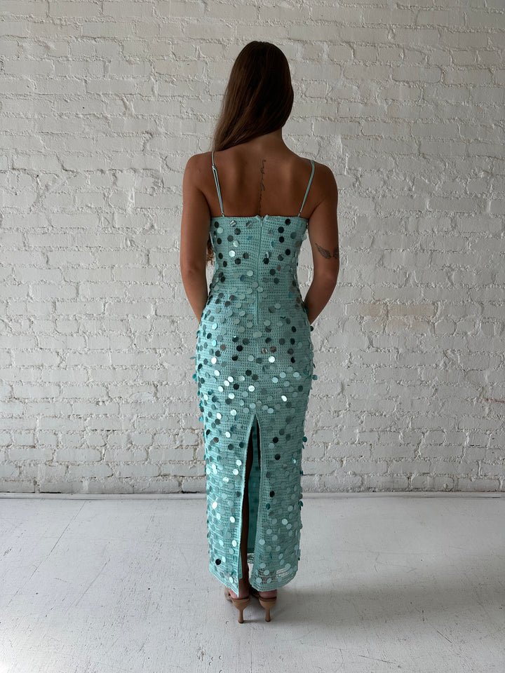 Woman wearing teal knit midi dress with sequin overlay. 