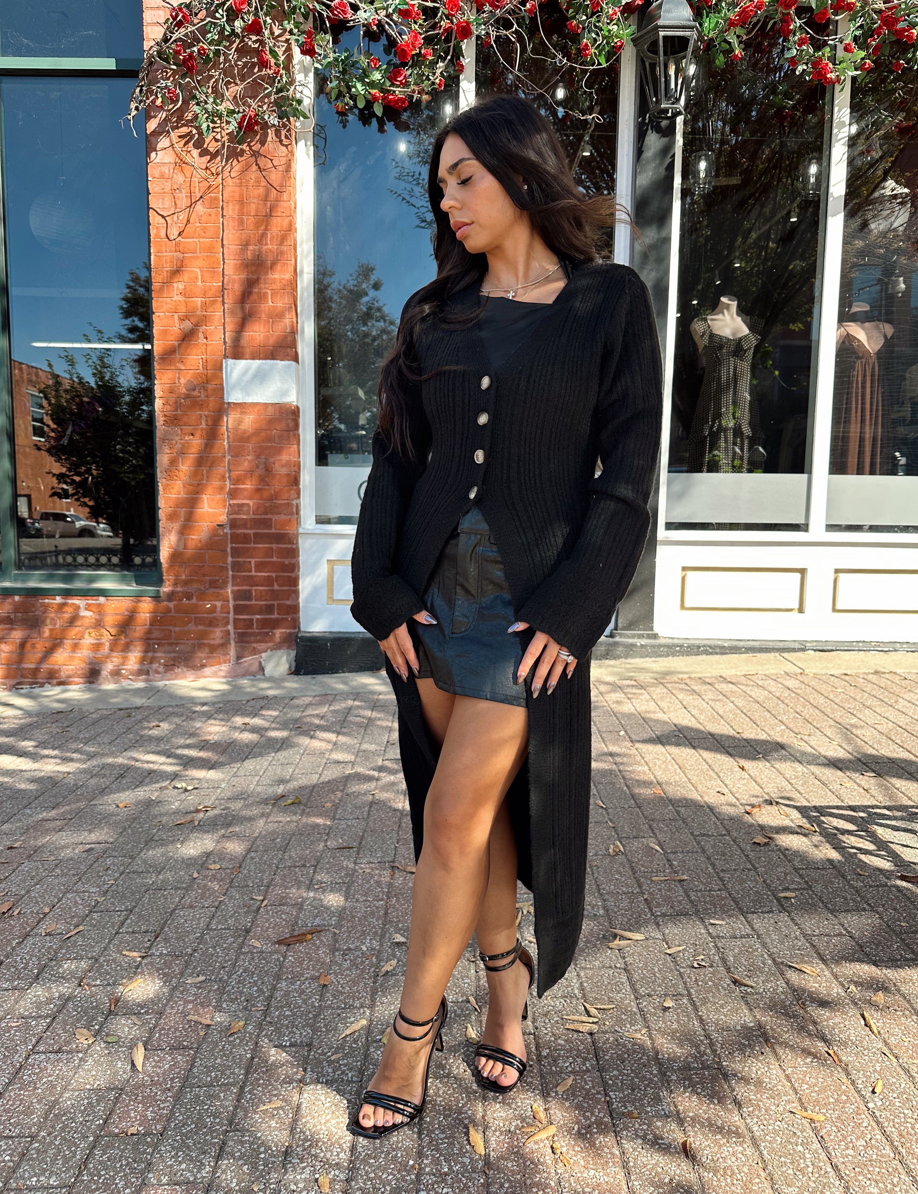 Woman wearing knit sweater duster cardigan with button closure. 