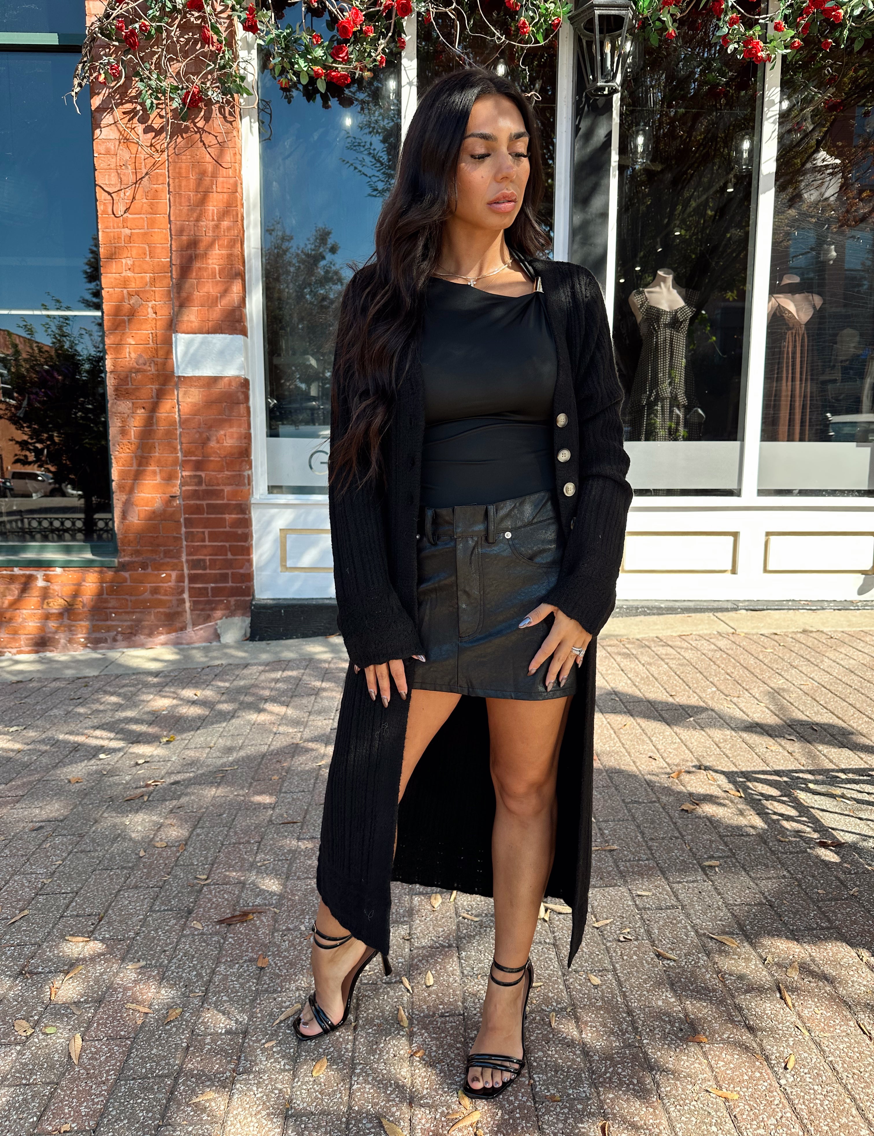 Woman wearing knit sweater duster cardigan with button closure. 