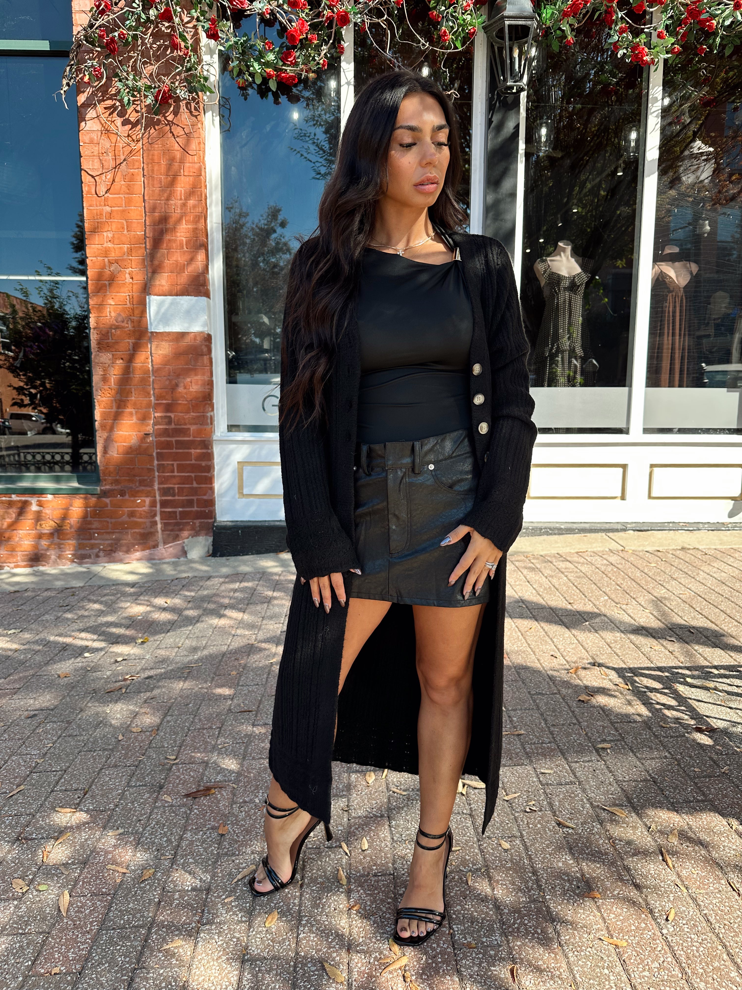 Woman wearing knit sweater duster cardigan with button closure. 