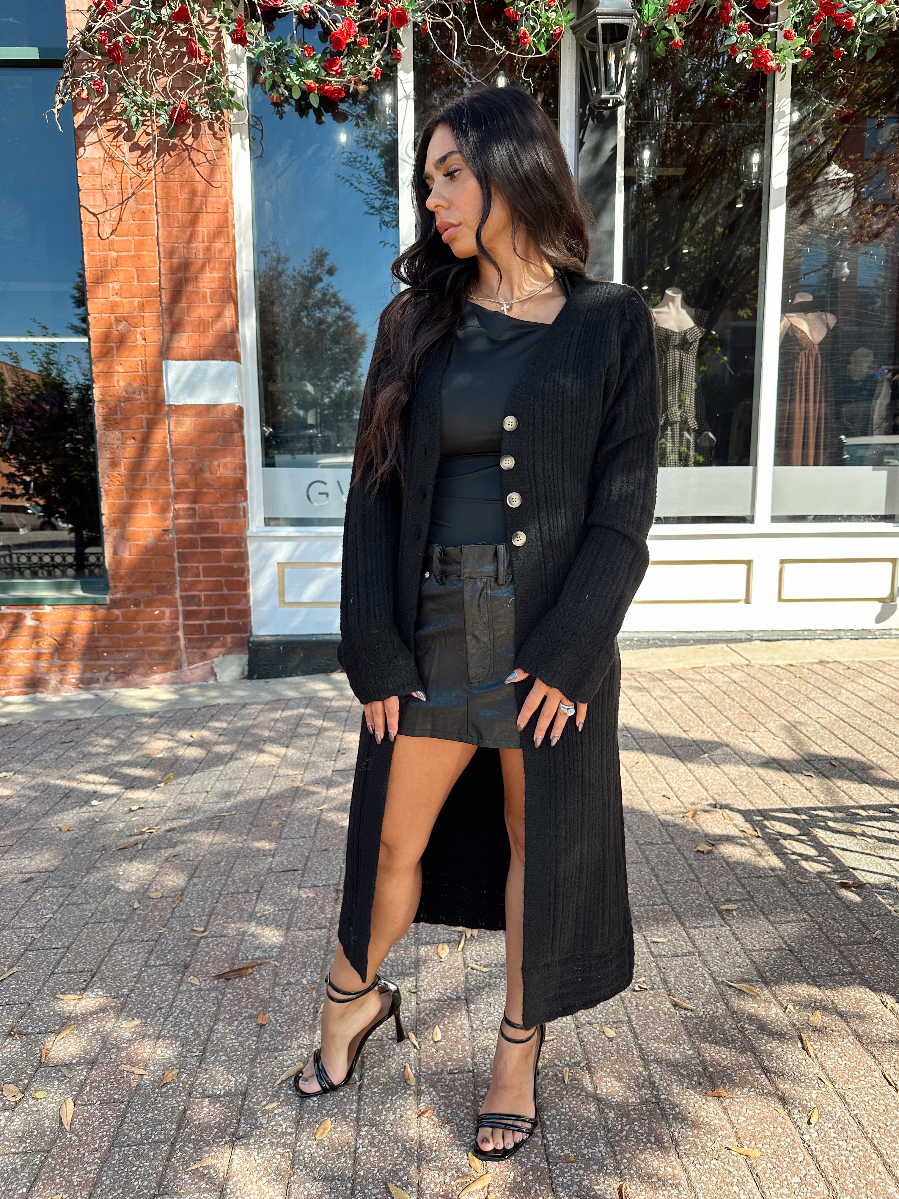 Woman wearing knit sweater duster cardigan with button closure. 