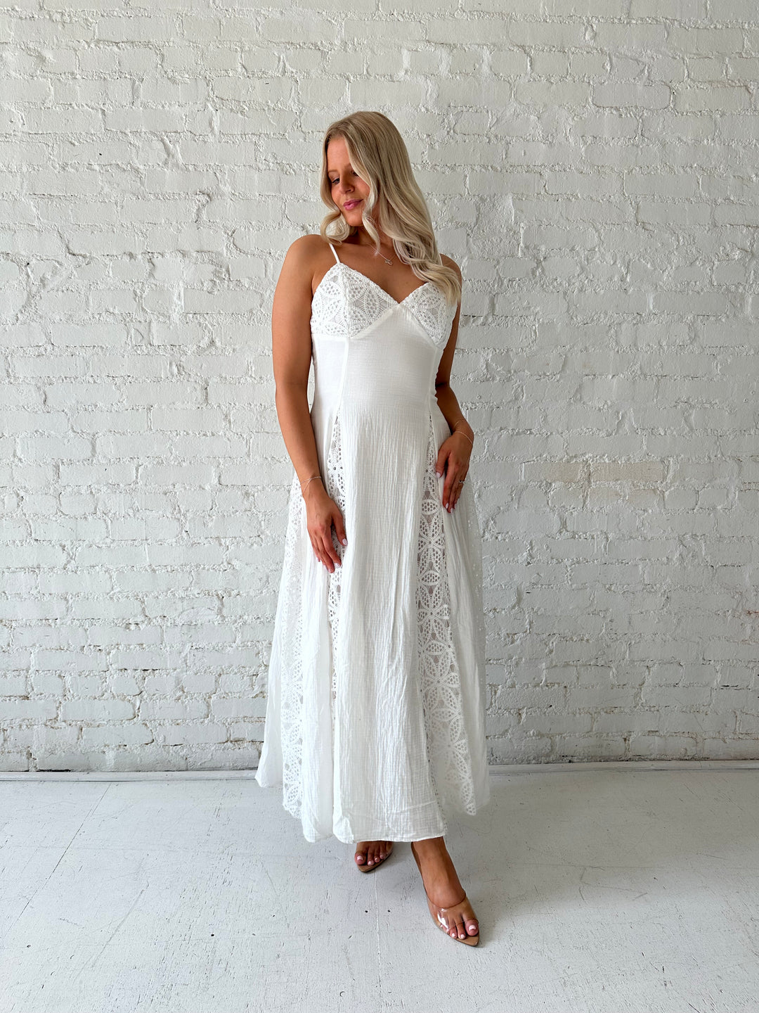 Woman wearing white maxi dress with eyelet lace detailing and adjustable spaghetti straps. 