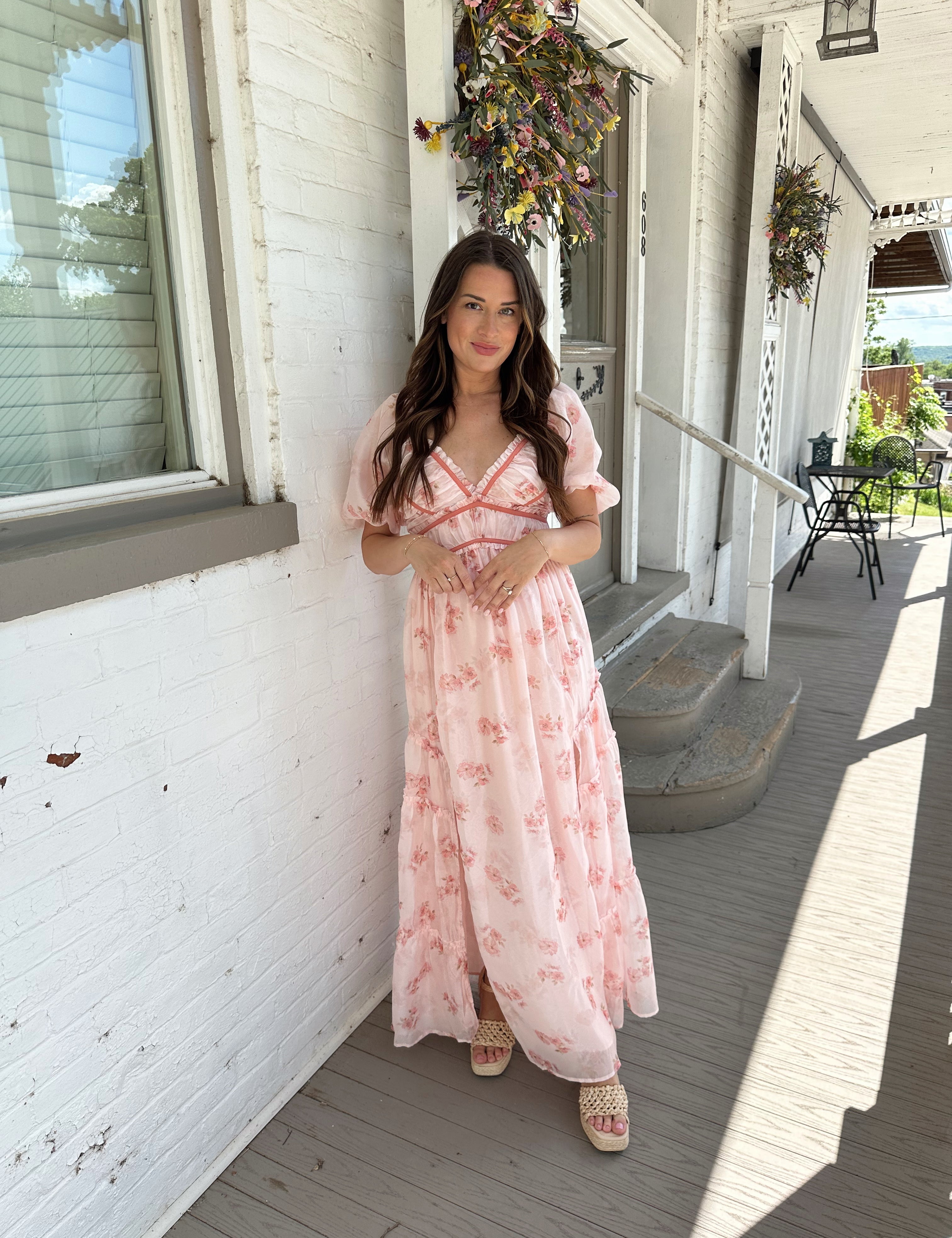 Woman in a pink floral maxi dress with puff sleeves, lace trim, and a subtle front slit