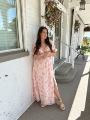 Woman in a pink floral maxi dress with puff sleeves, lace trim, and a subtle front slit