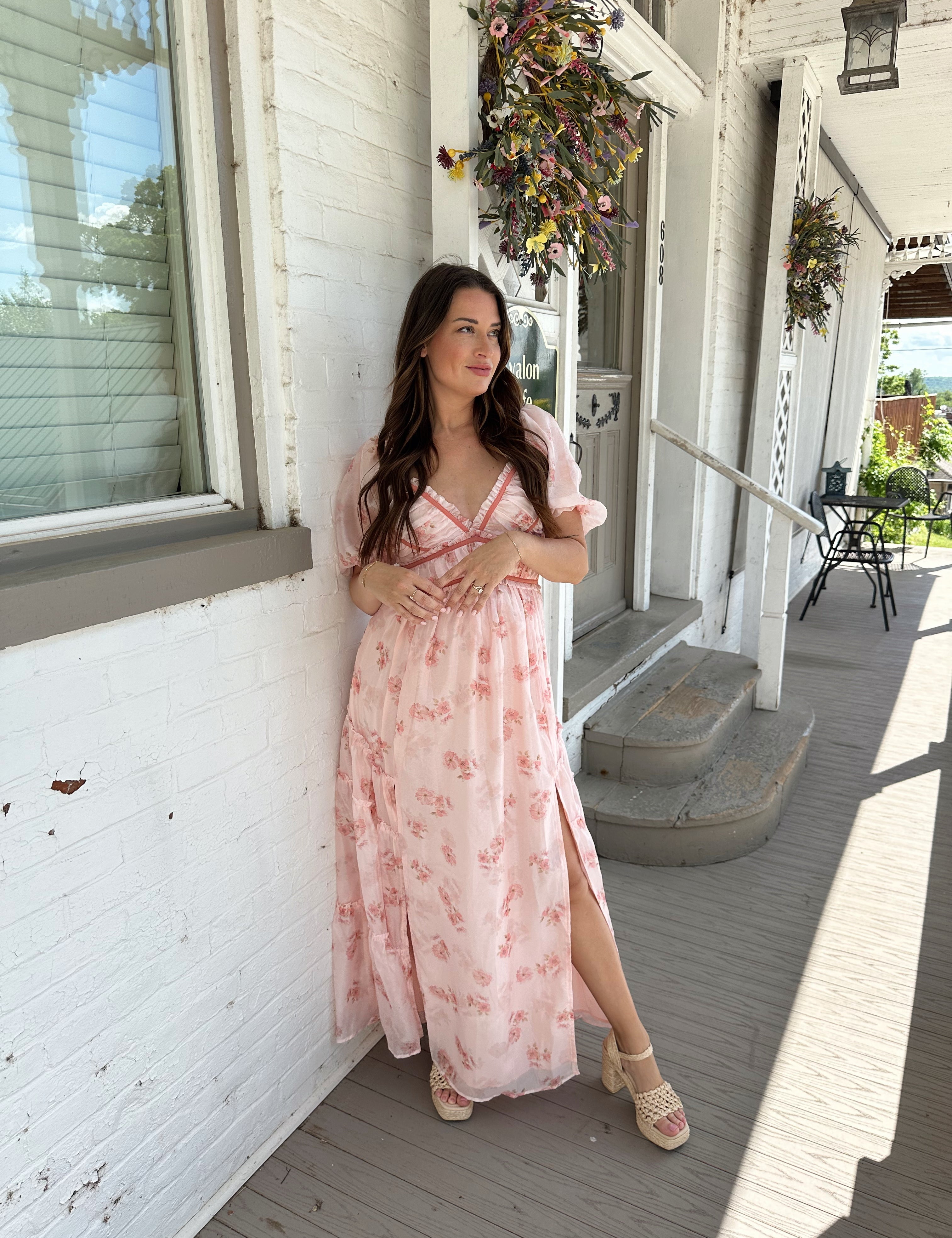 Woman in a pink floral maxi dress with puff sleeves, lace trim, and a subtle front slit