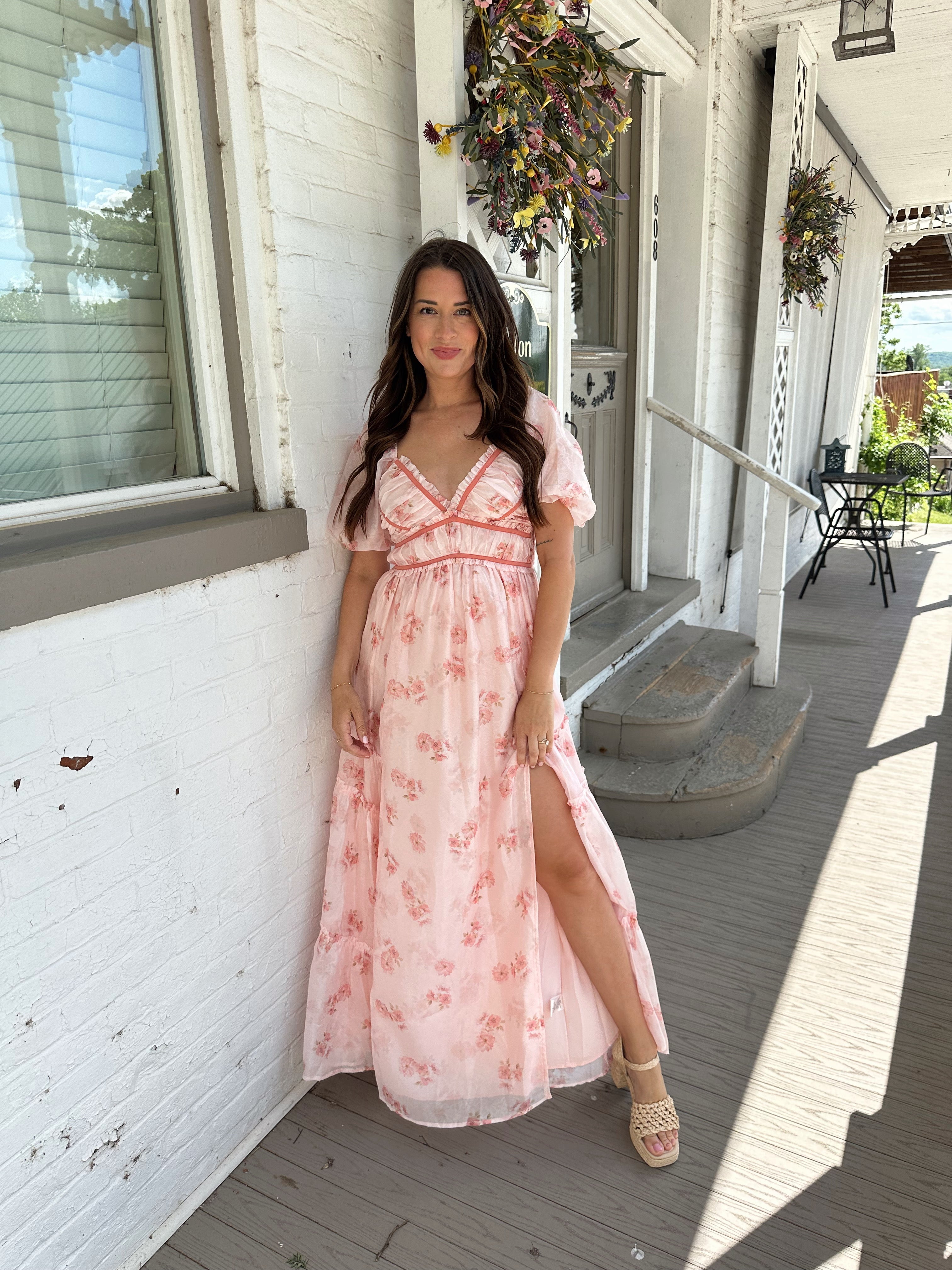 Woman in a pink floral maxi dress with puff sleeves, lace trim, and a subtle front slit