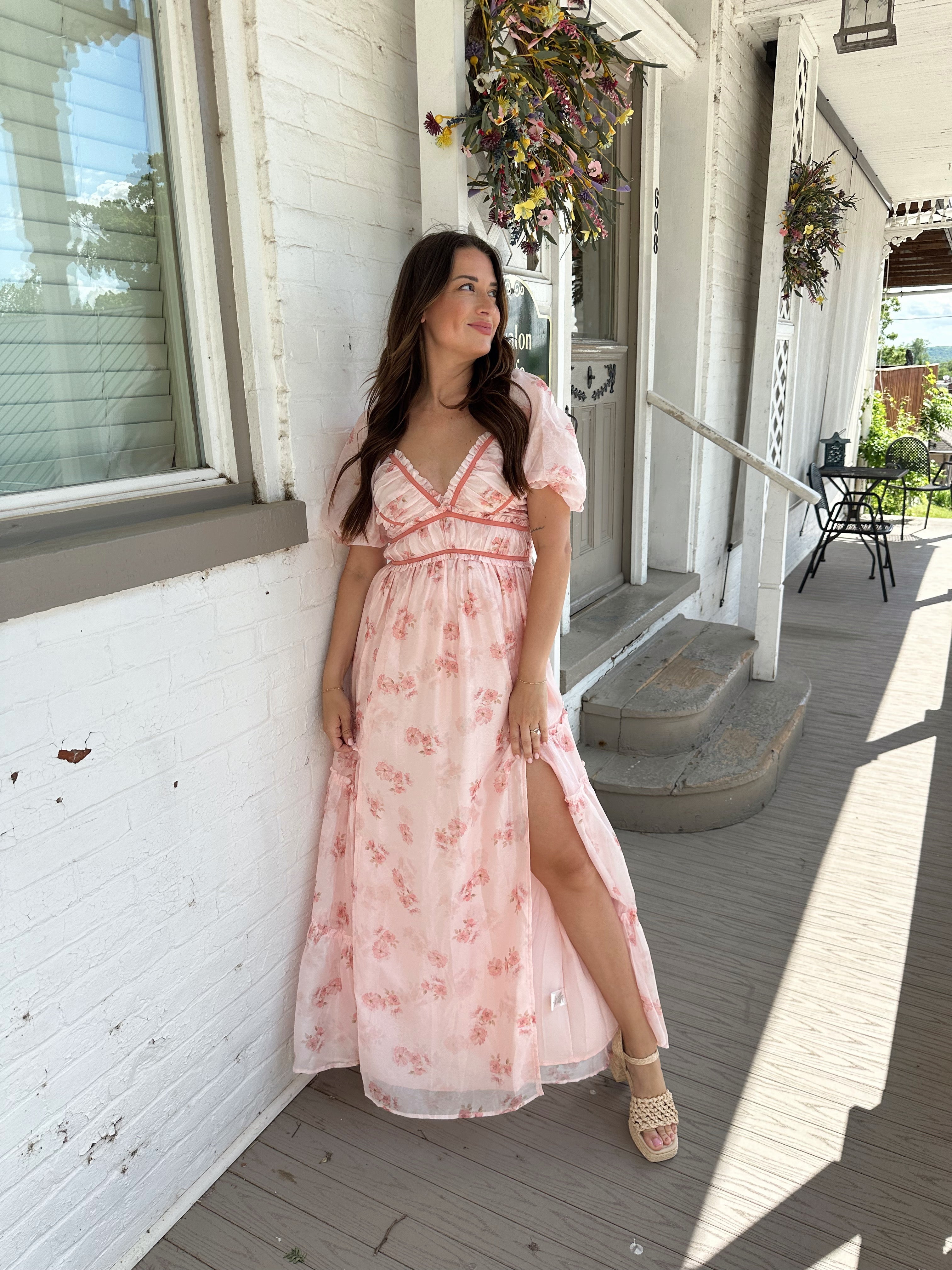 Woman in a pink floral maxi dress with puff sleeves, lace trim, and a subtle front slit