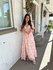 Woman in a pink floral maxi dress with puff sleeves, lace trim, and a subtle front slit