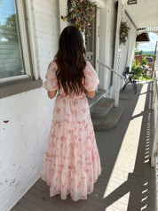 Woman in a pink floral maxi dress with puff sleeves, lace trim, and a subtle front slit