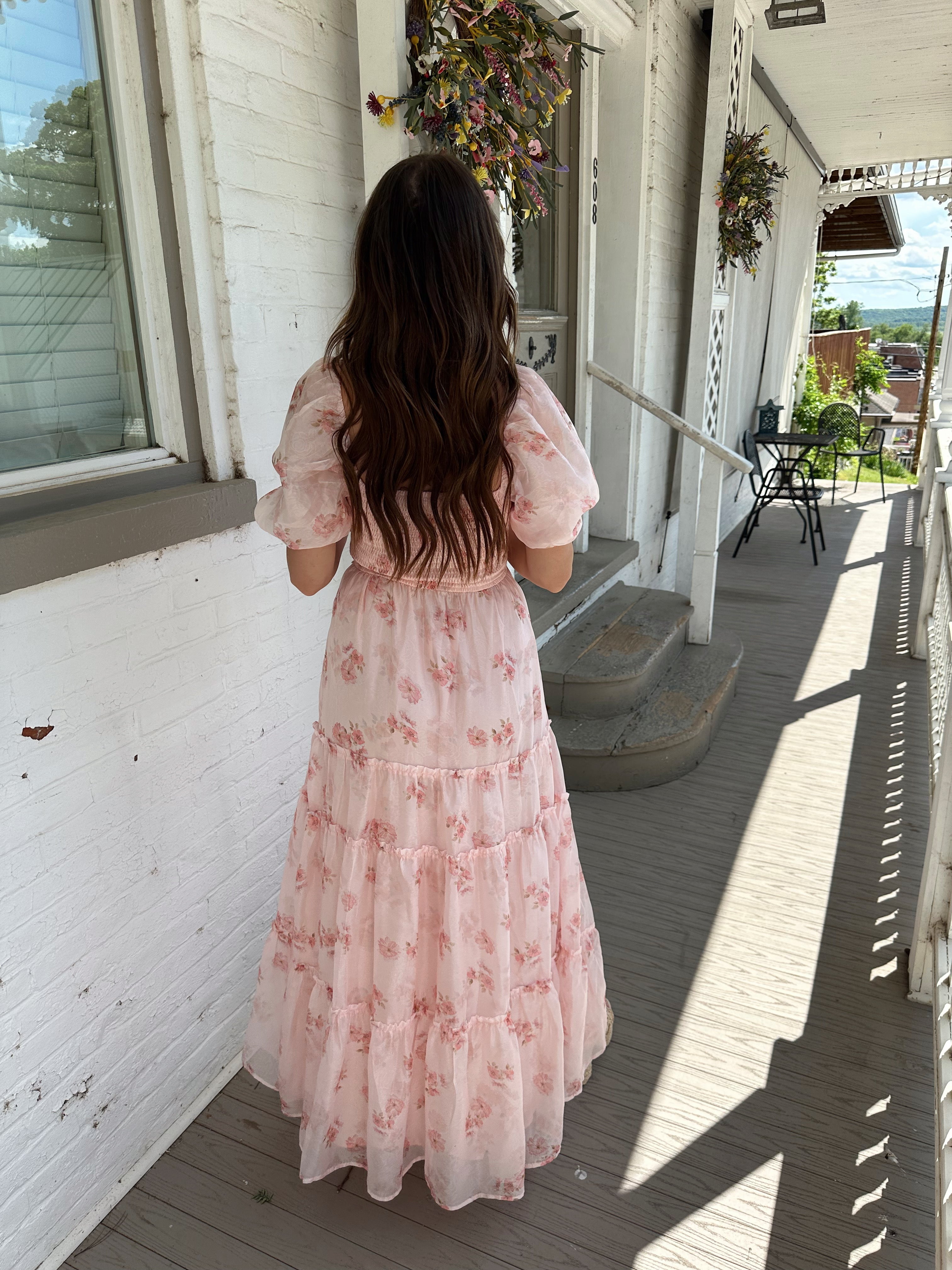Woman in a pink floral maxi dress with puff sleeves, lace trim, and a subtle front slit