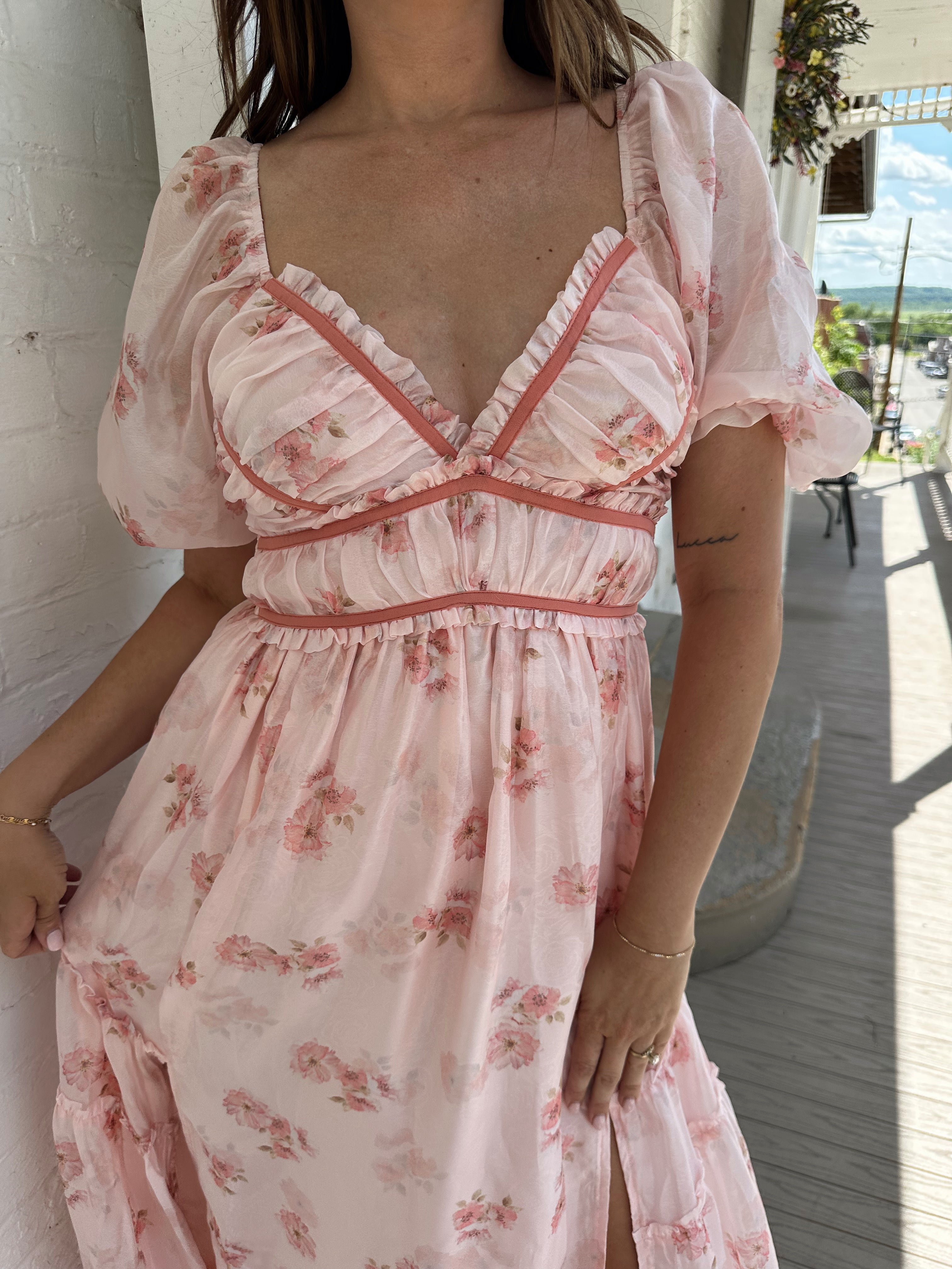 Woman in a pink floral maxi dress with puff sleeves, lace trim, and a subtle front slit